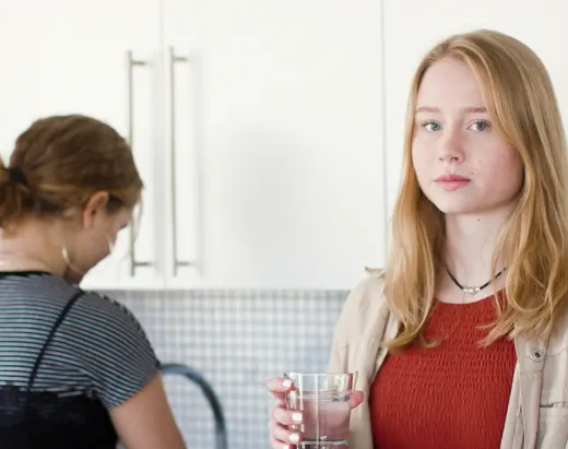 To tenåringsjenter tar seg et glass vann på kjøkkenet i en barnevernsinstitusjon.