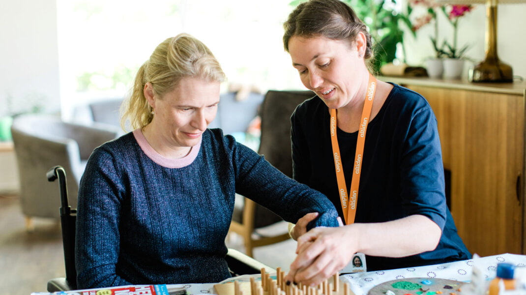 Beboer får hjelp til kreativ aktivitet av en ansatt