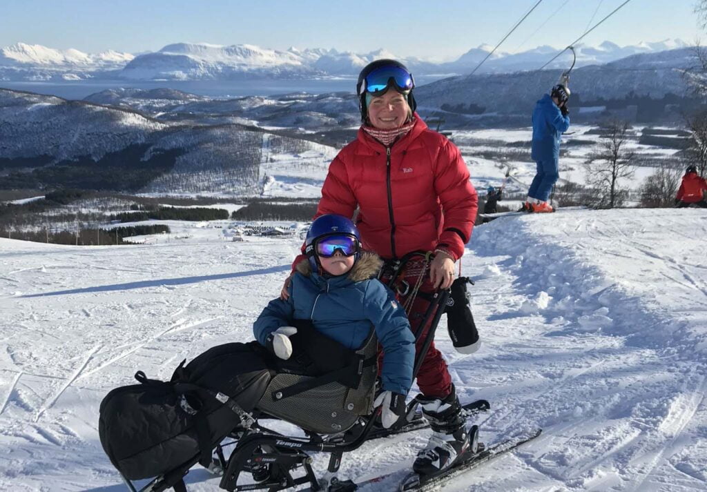 Barn med sitski og mor i alpinbakke