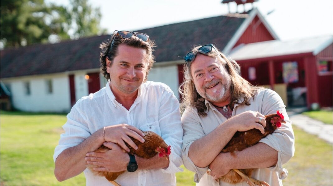 To menn bærer hver sin høne foran en gård