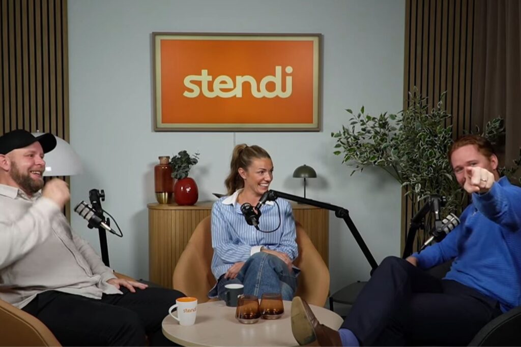 To menn og en kvinne ler i podcaststudio