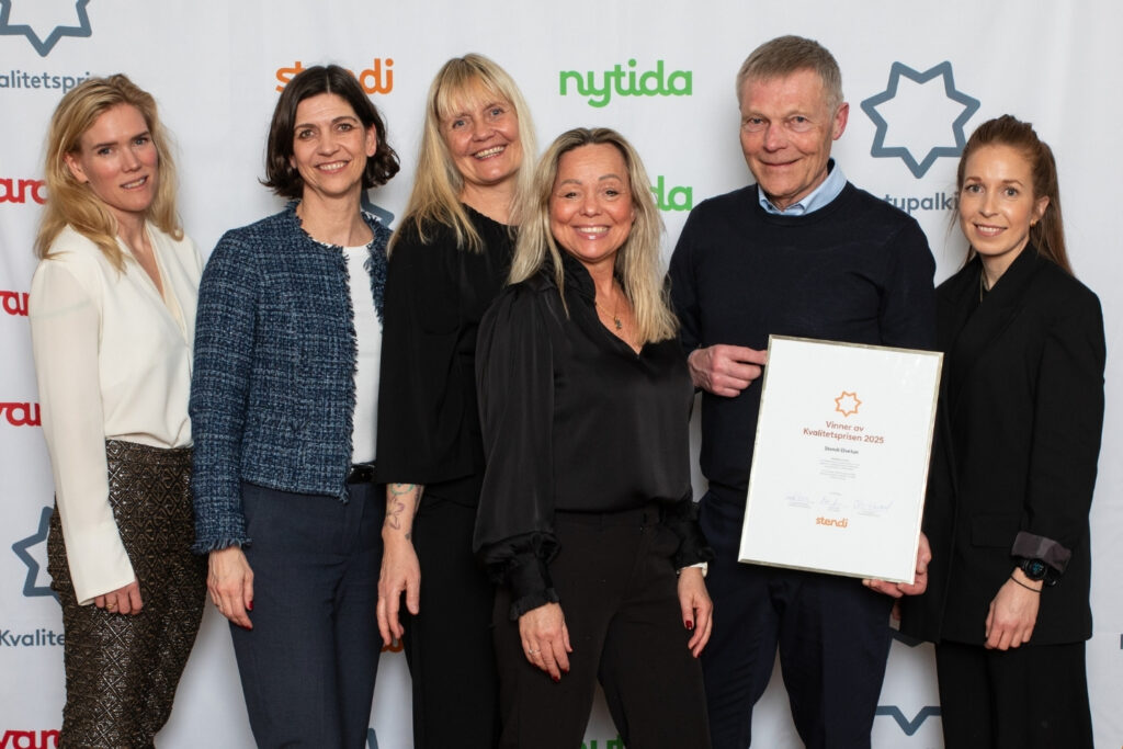En gruppe mennesker  på seks viser frem en innrammet kvalitetspris.