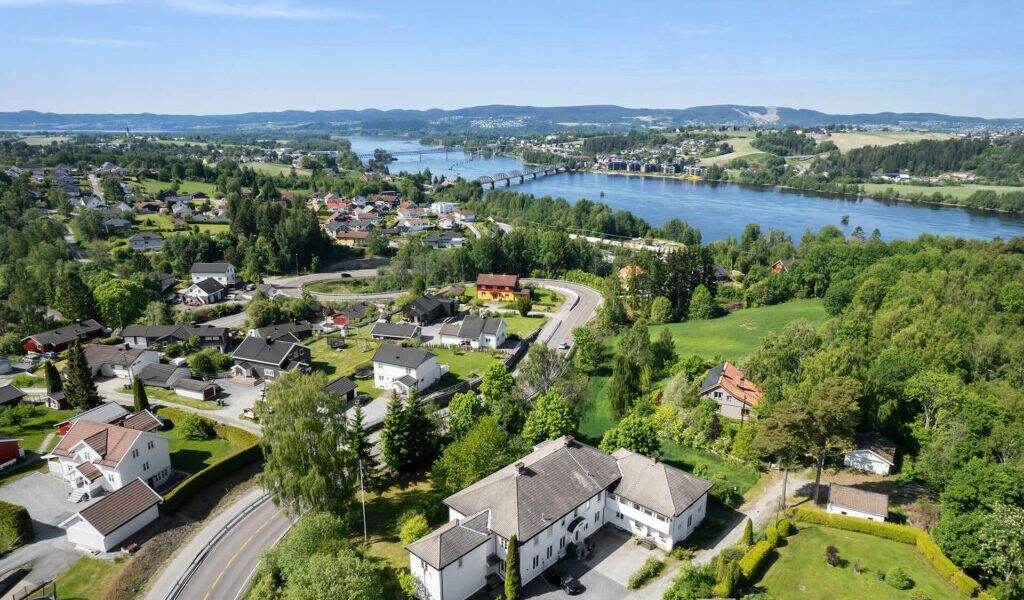 Hvitmalt herskapspolig i grønne omgivelser og elv i nærheten. Dronebilde.