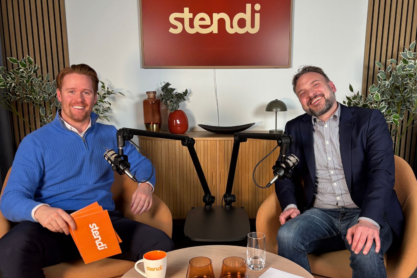 To smilende menn sitter i hver sin lenestol i Stendi-studio